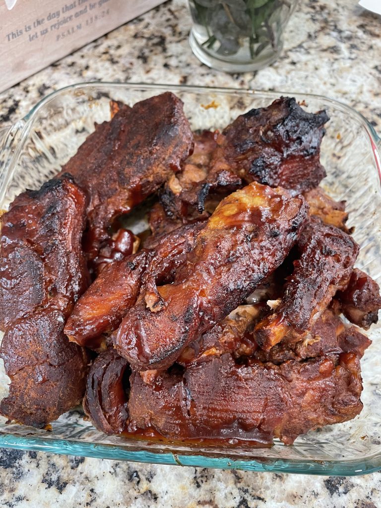 A glass bowl of cooked and broiled BBQ ribs