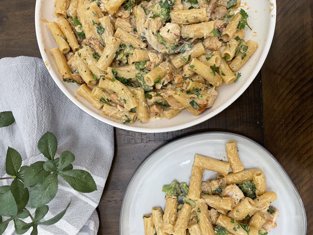 A bowl of pasta, chicken, broccoli and spinach