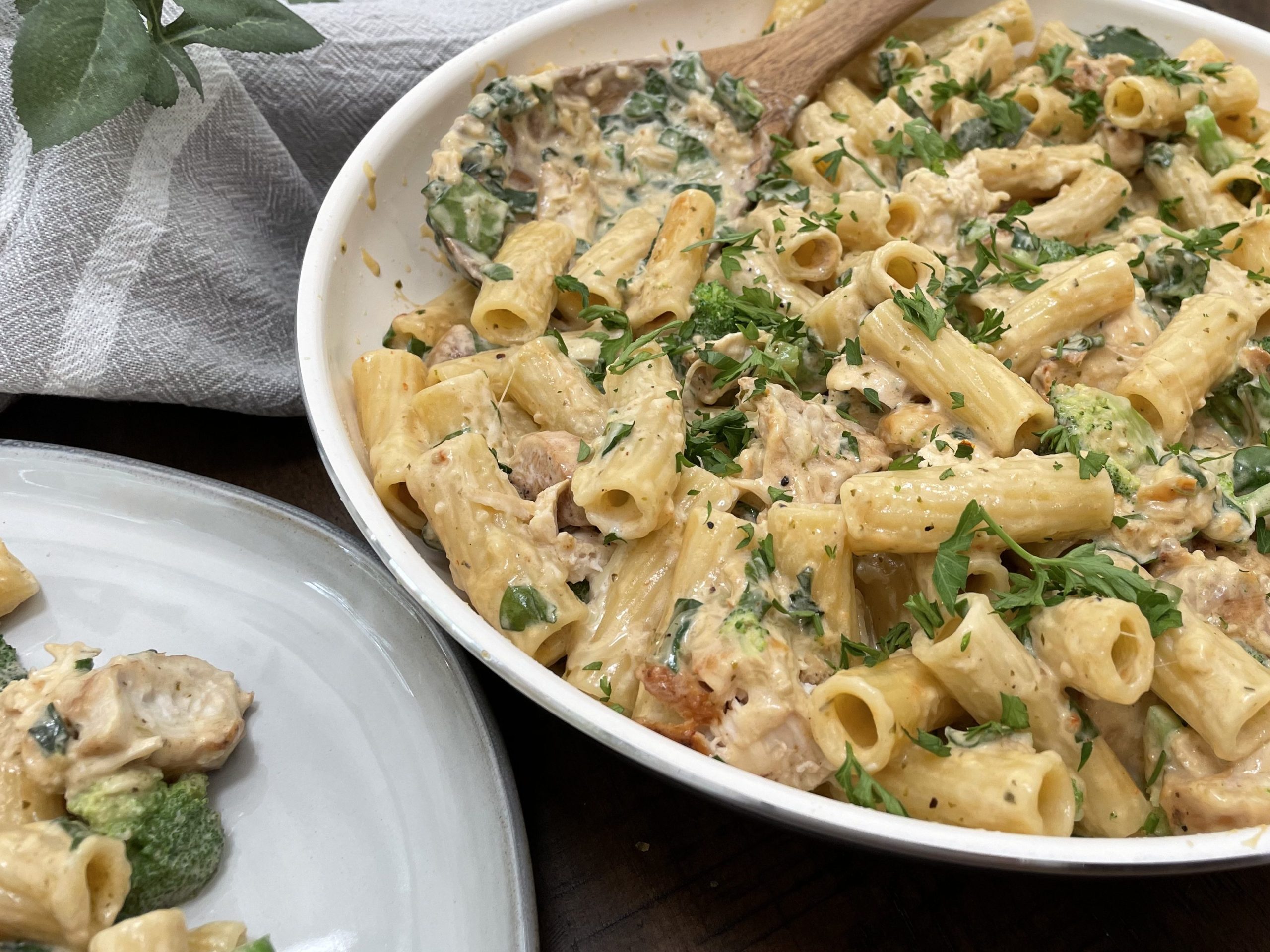 A pan of pasta, chicken, broccoli and spinach.