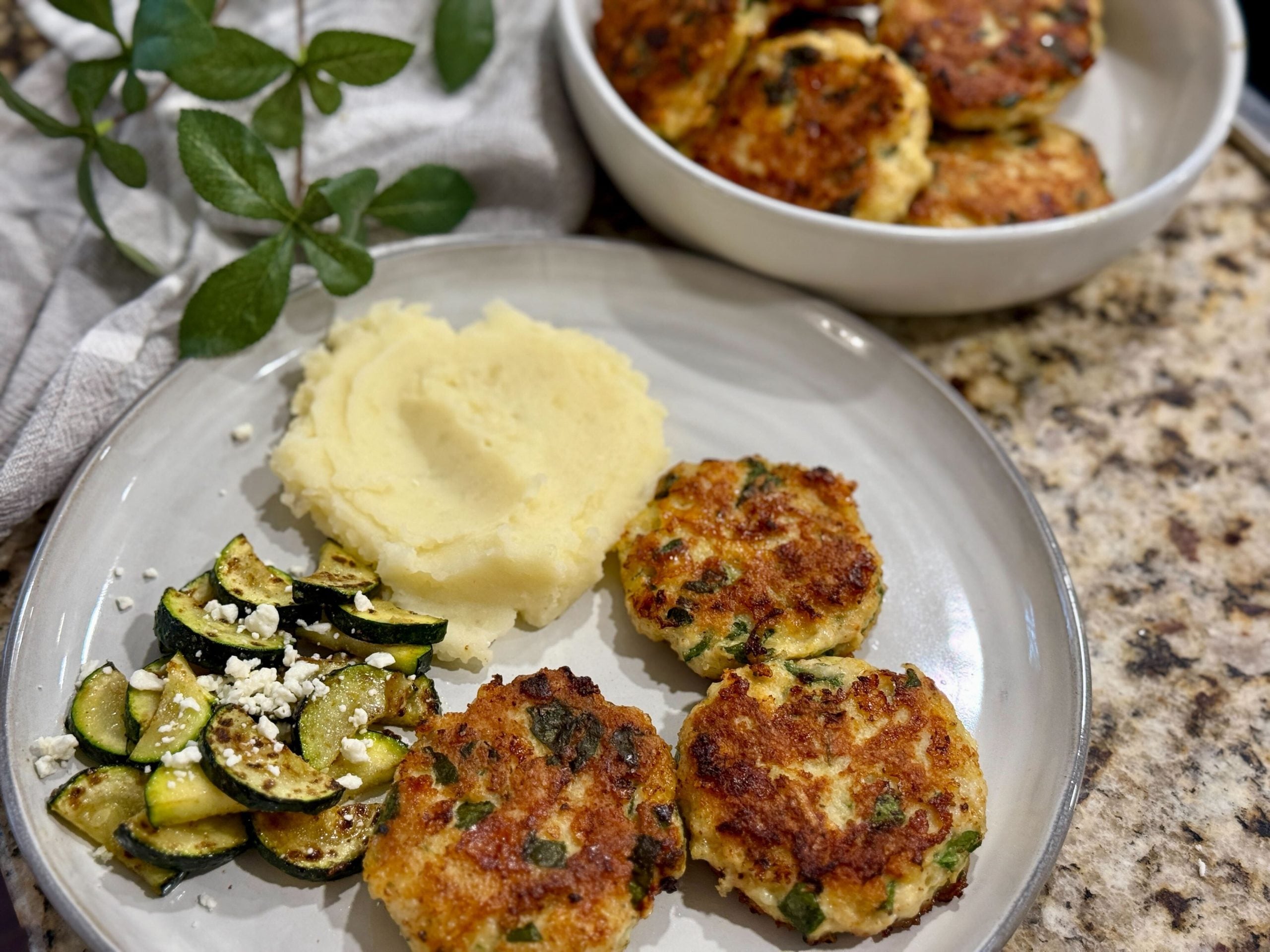 Cheesy Chicken Fritters on a plate with mashed potatoes, zucchini and feta cheese
