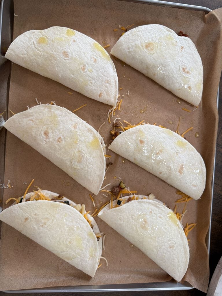 Flour tortillas folded over on a baking sheet