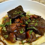 a bowl with chunks of beef, mashed potatoes and carrots