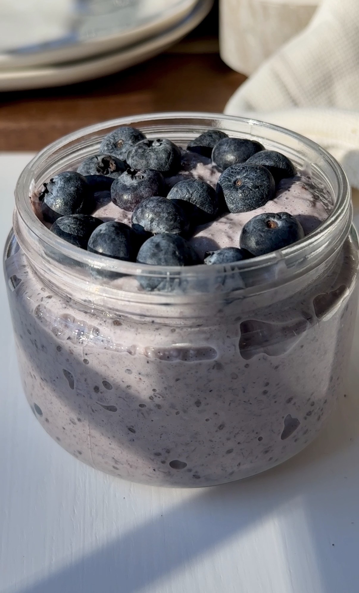 Screenshot A glass jar with blended blueberry overnight oats, topped with more fresh blueberries