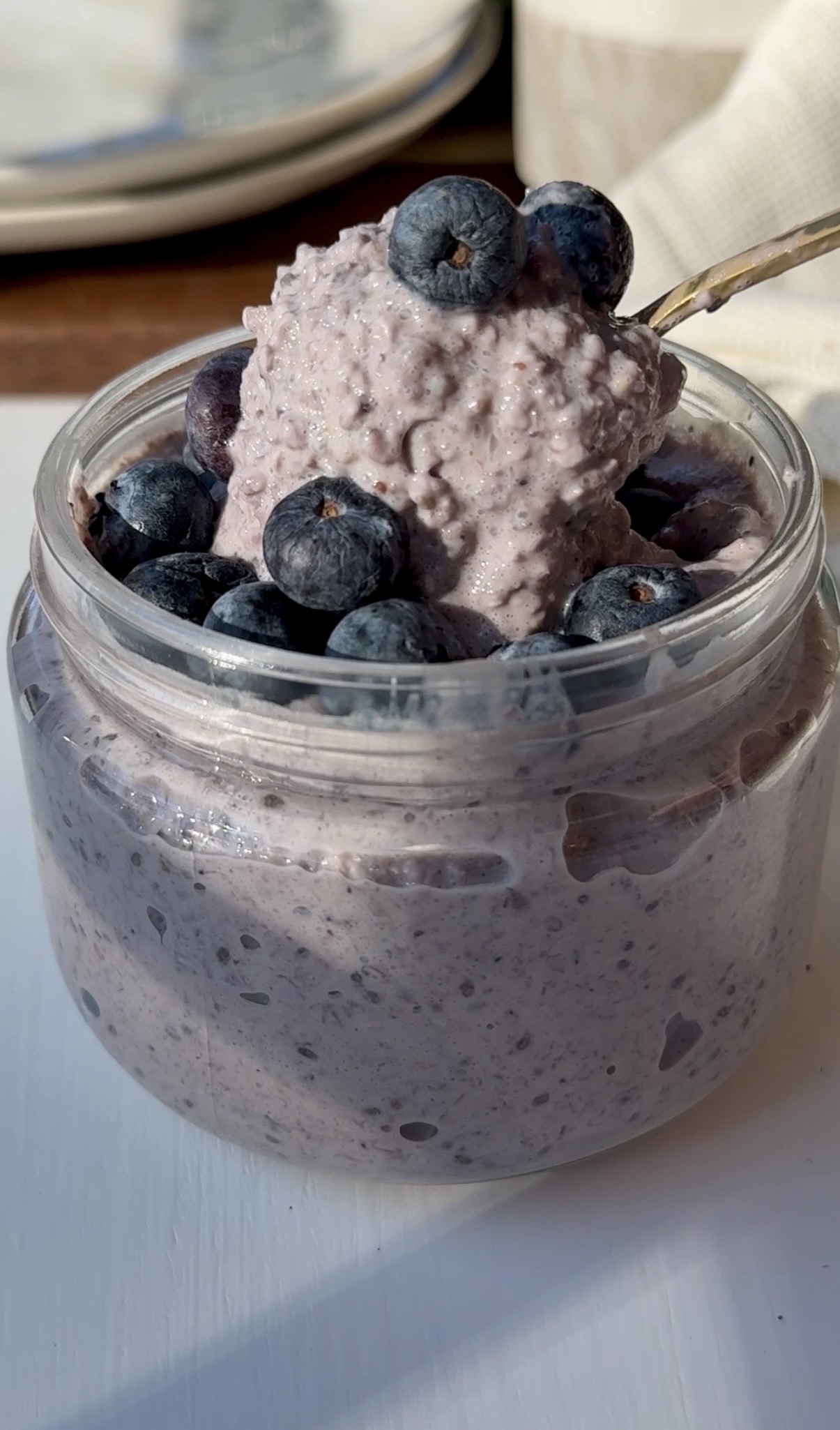 Screenshot A glass jar with blended blueberry overnight oats, topped with more fresh blueberries
