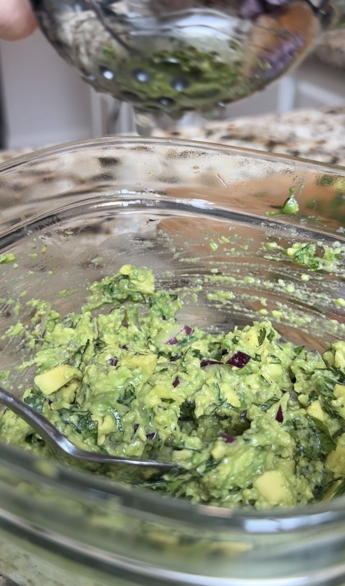 A glass bowl with guacamole and a lime squeezer.