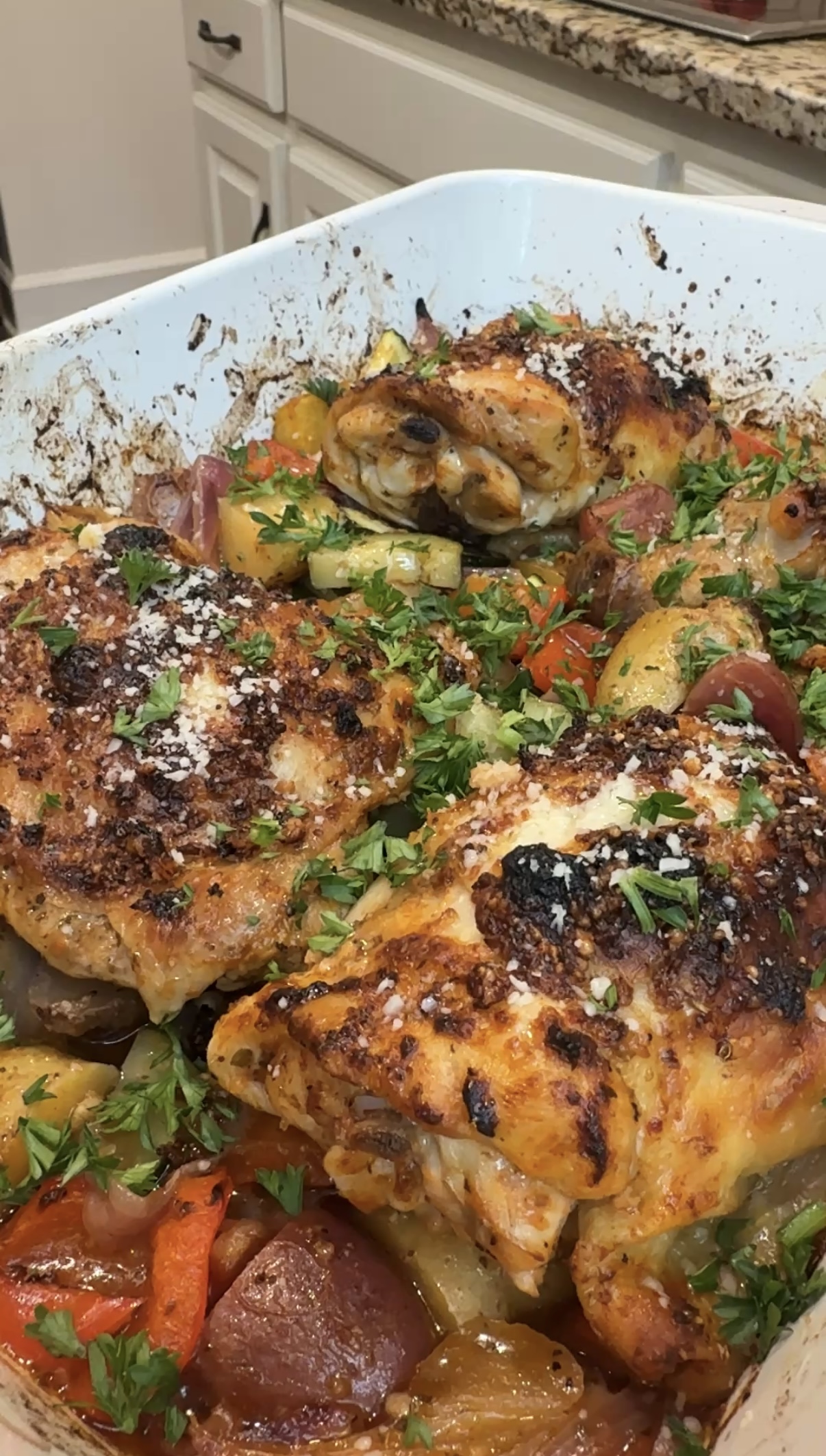 A baking dish with veggies and greek chicken thighs