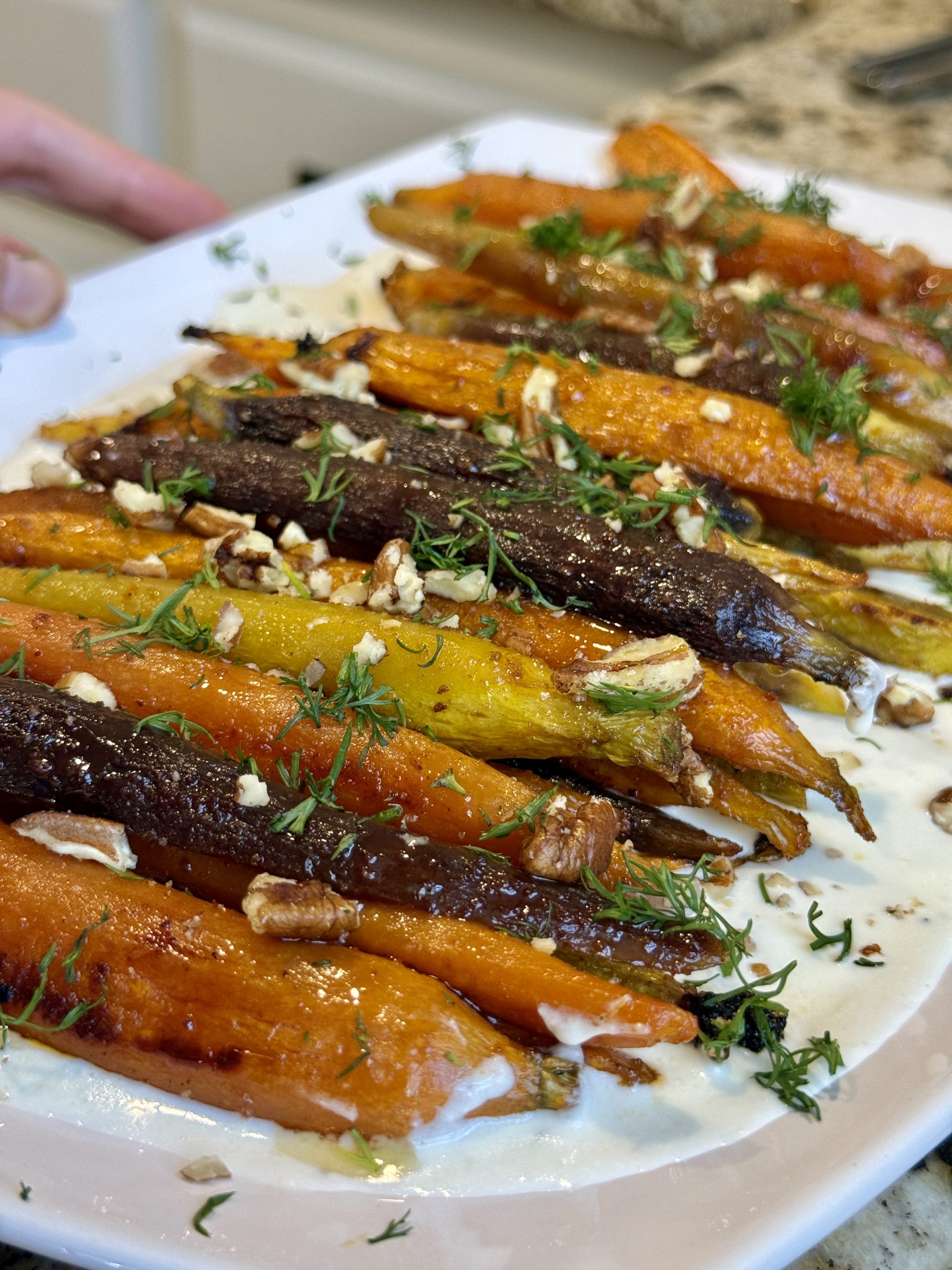 A platter with whipped feta and carrots, sprinkled with dill and pecans