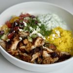 A bowl of chicken gyro meat, rice, tzatziki sauce, and Greek salad