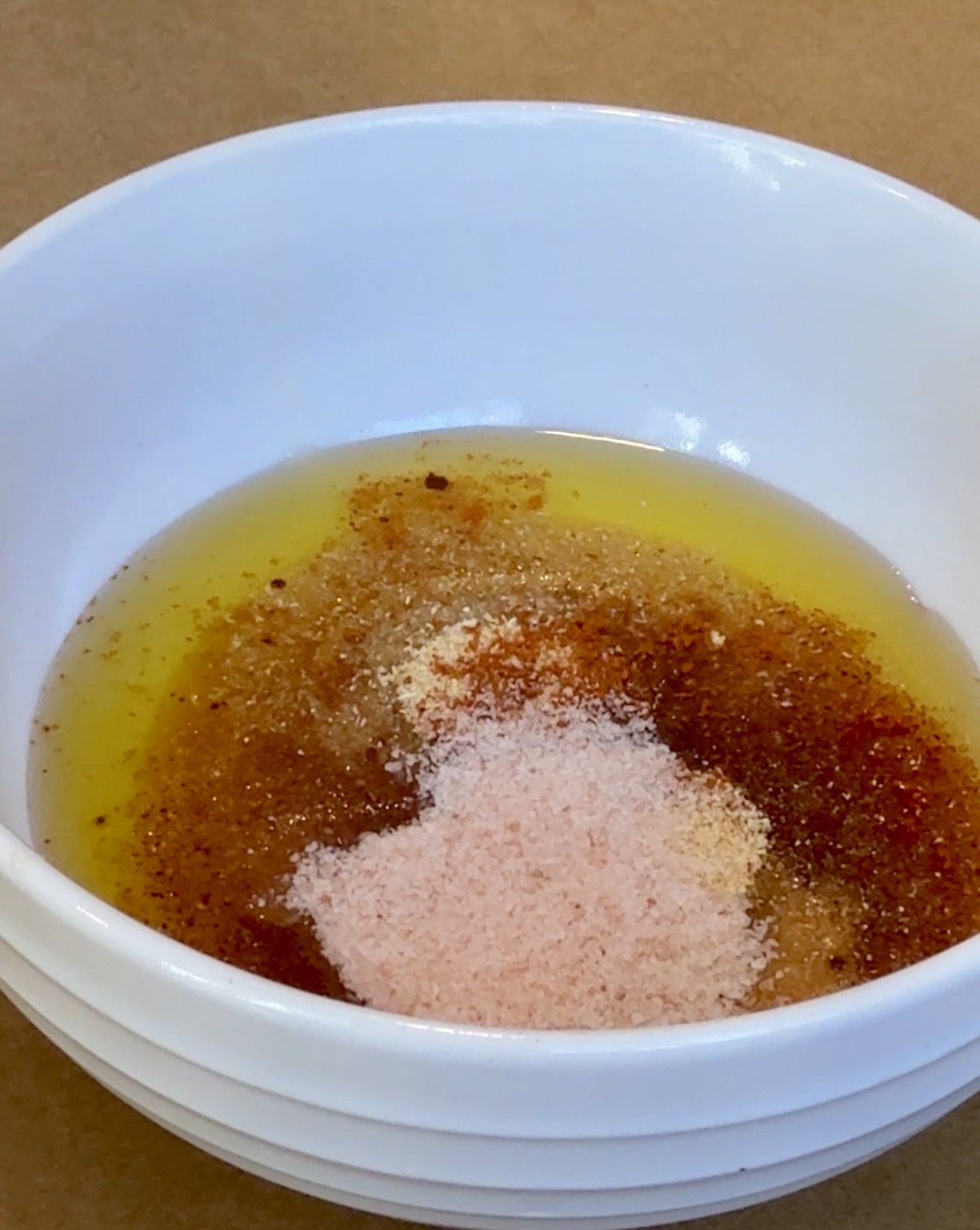 Olive oil with lemon and seasonings in a white bowl