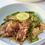 A plate of lemon chicken orzo garnished with a lemon slice.