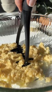 Bananas being mashed with a potato masher