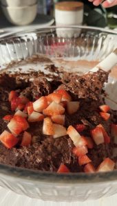 A glass bowl with the muffin mixture and added fresh chopped strawberries