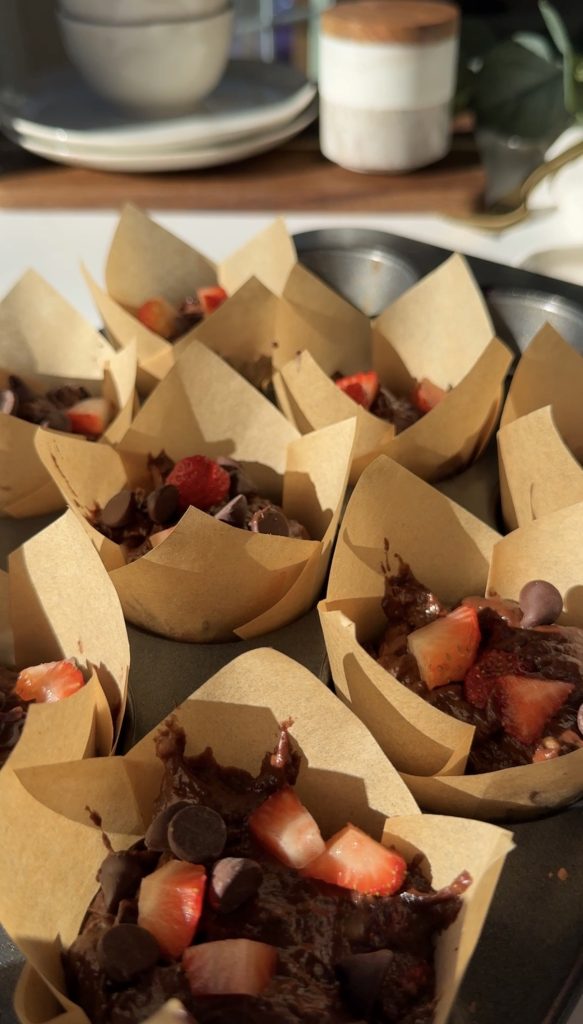 Muffin tin pan, lined with paper muffin liners and filled with the muffin mixture and topped with fresh strawberries