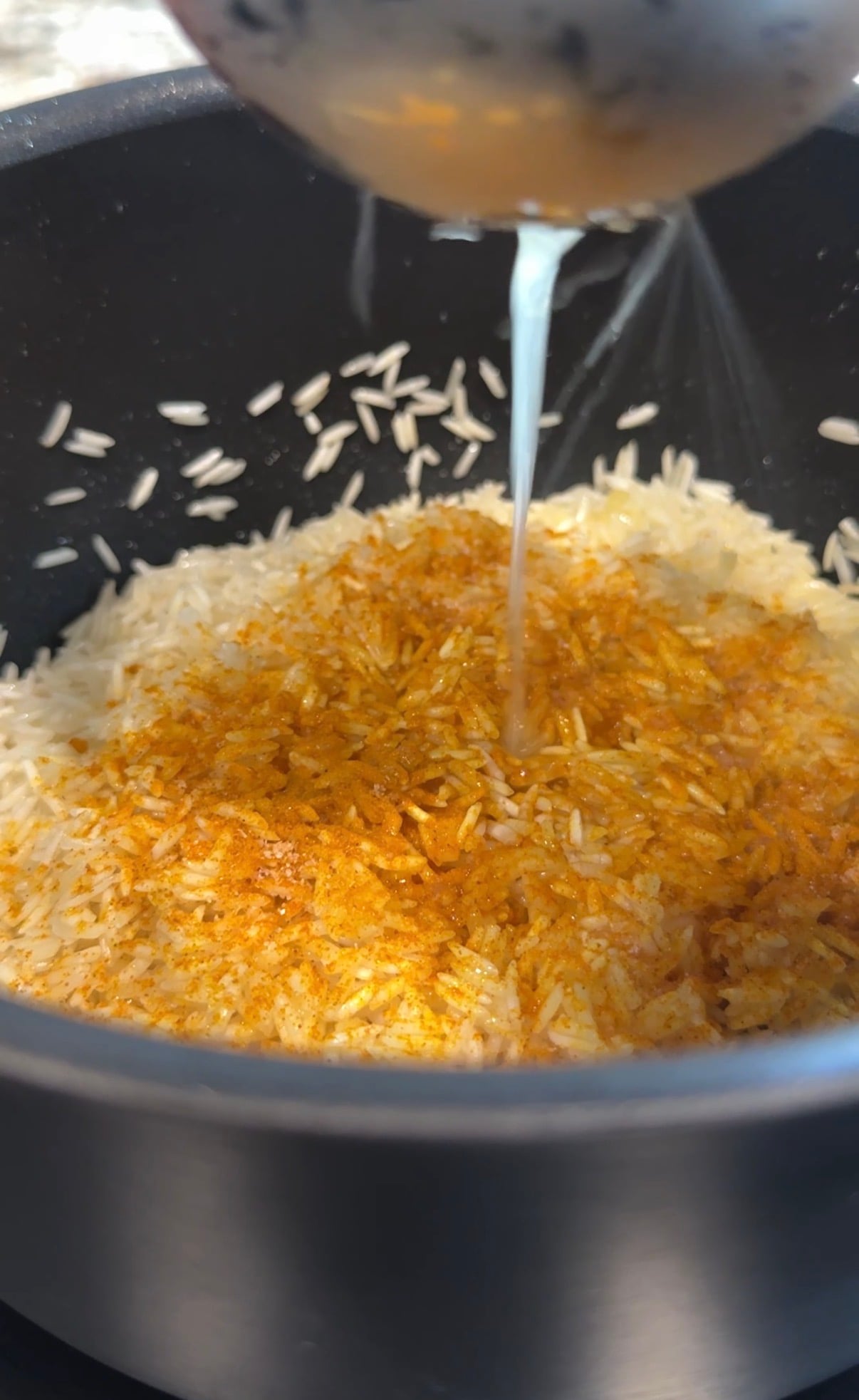 A cooking pot with turmeric rice and lemon juice being poured into it