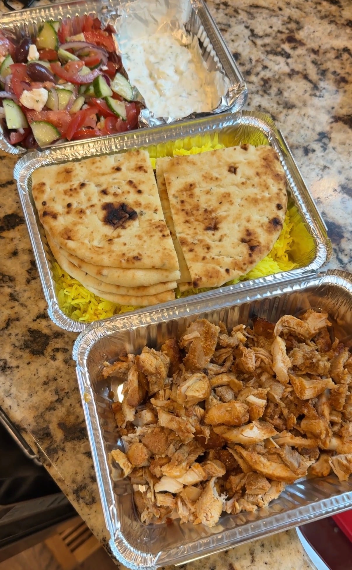 Screenshot Three meal prep containers: one with gyro chicken, one with turmeric rice and pita bread and one with Greek salad and tzatziki sauce.