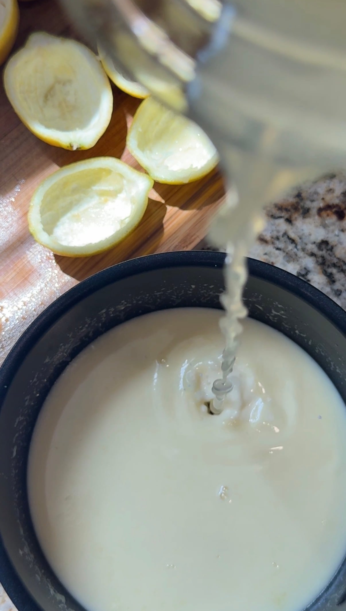 Heavy cream in a sauce pan and lemon juice being poured into it