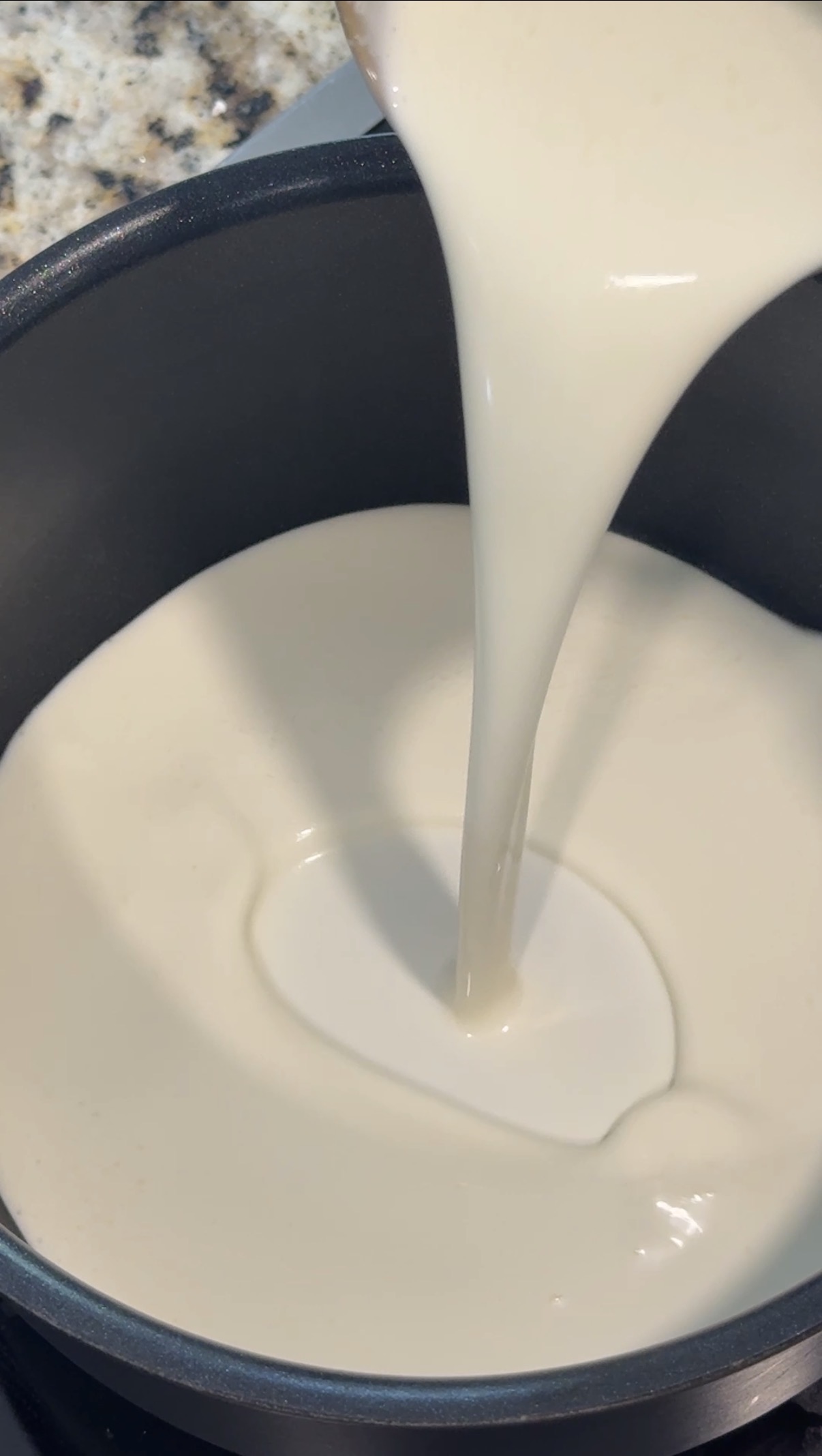 A sauce pan and heaving cream pouring into it