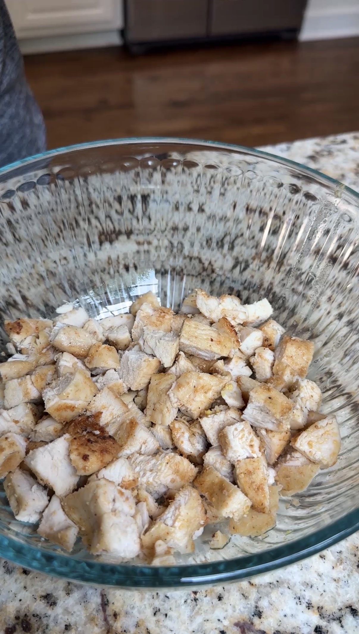 A glass bowl with diced cooked chicken