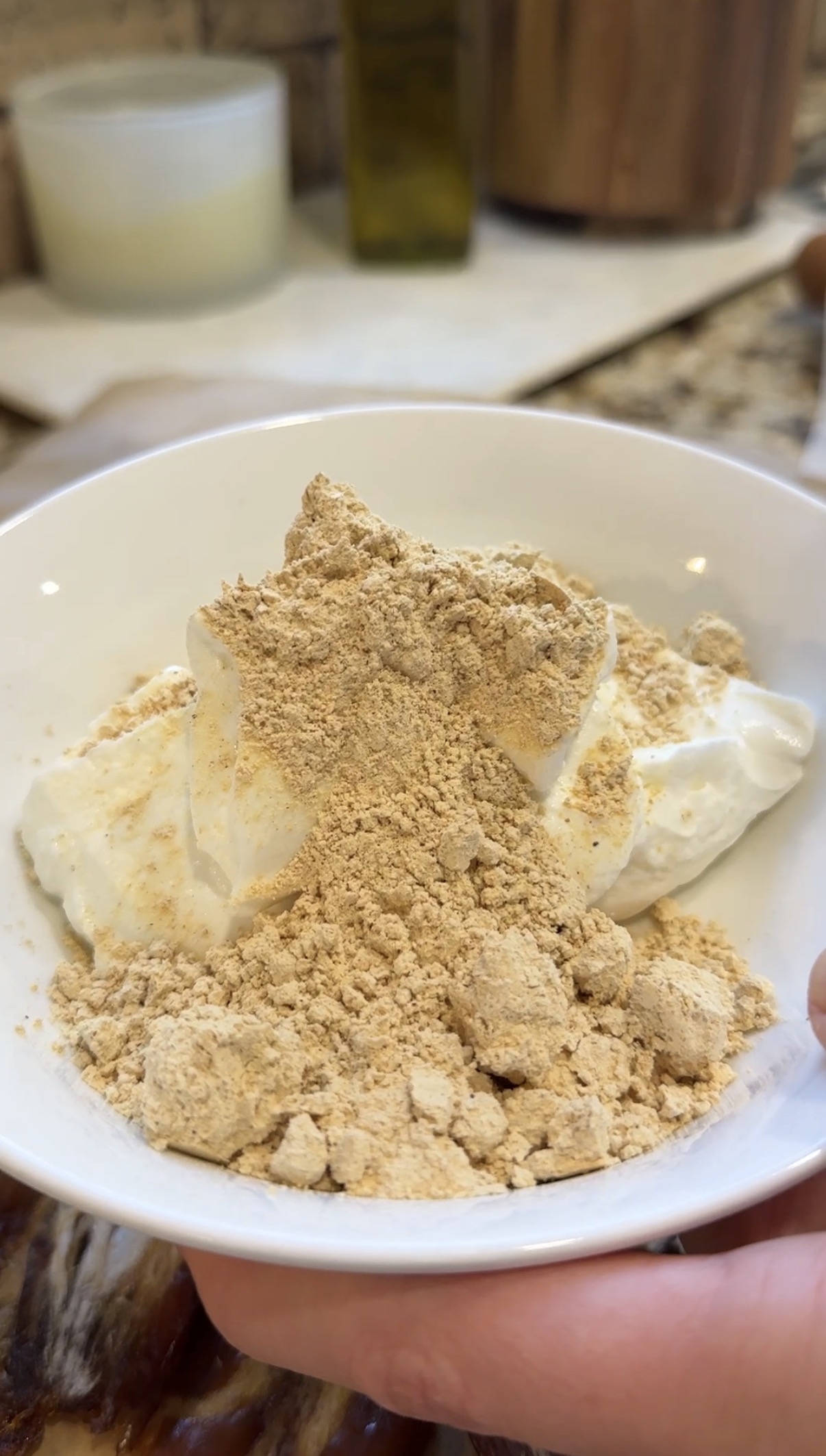 A white bowl filled with creamy yogurt topped with a generous amount of peanut butter powder.