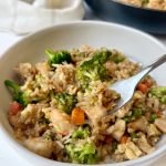 A bowl of shrimp and chicken fried rice with a fork holding up a bite.