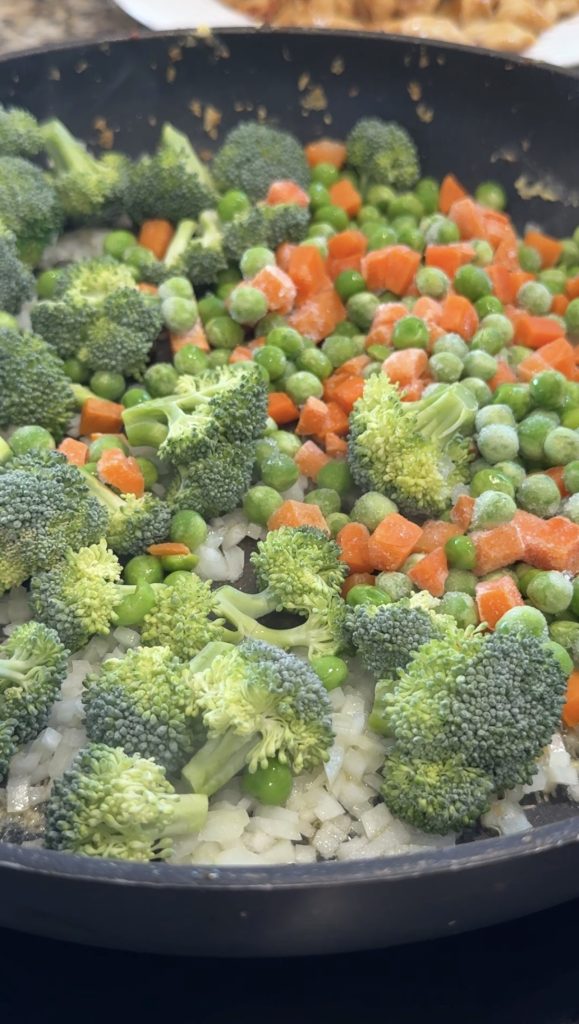Vegetables added to a skillet to cook. 