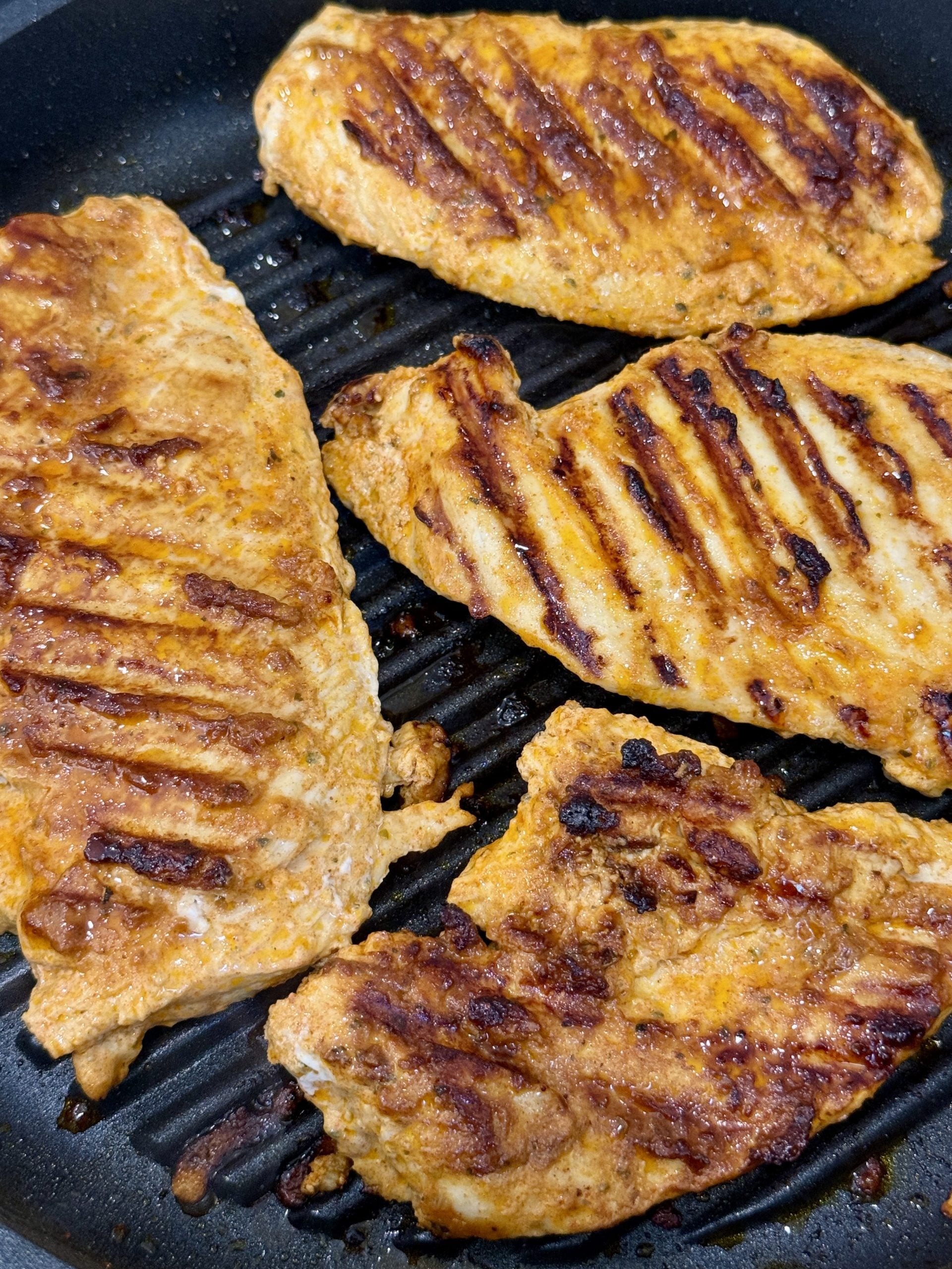 Yogurt marinated chicken grilling on a grill.