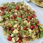 Pesto orzo pasta salad on a platter drizzled with balsamic glaze.