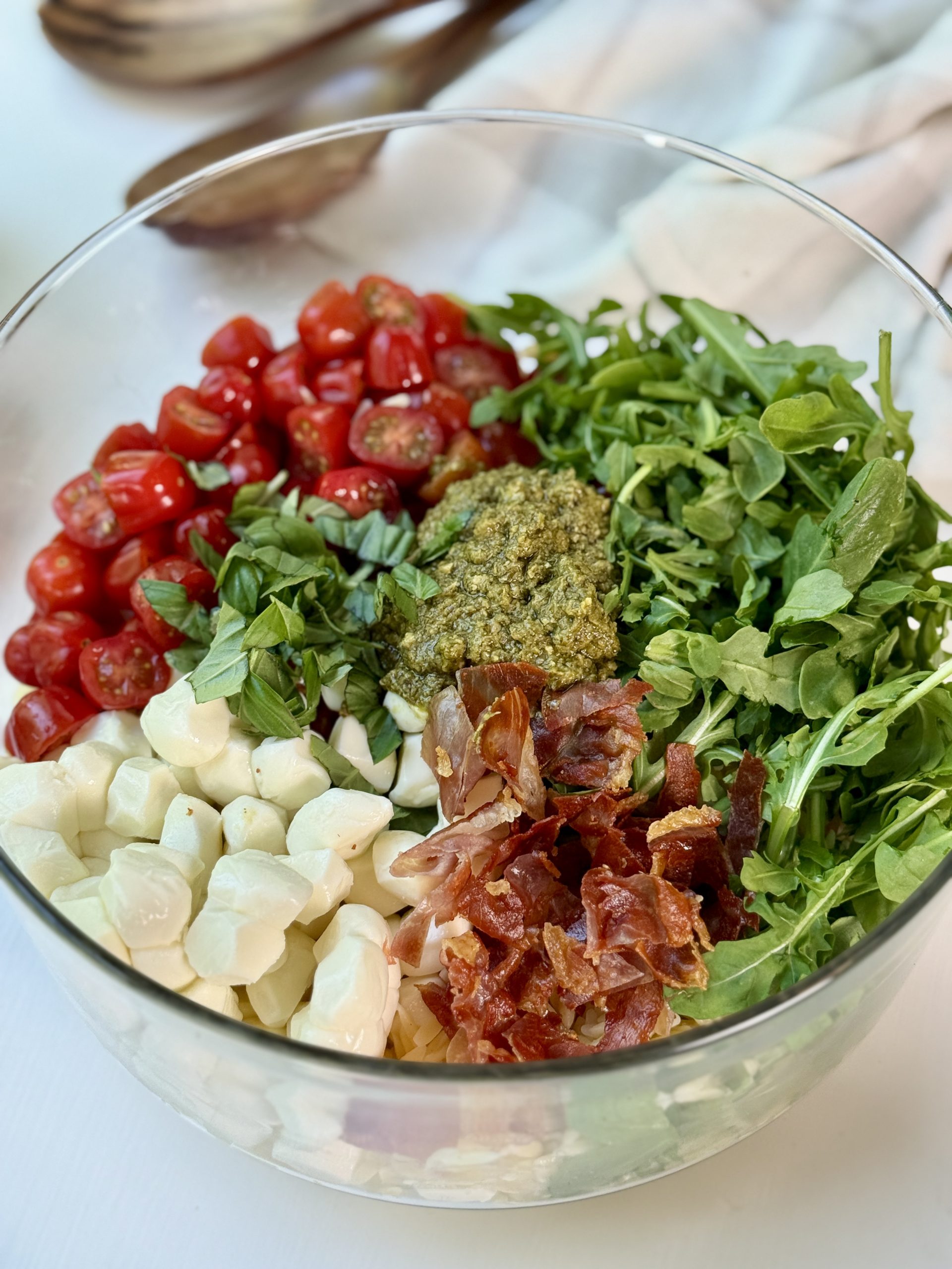 Pesto orzo pasta salad ingredients added to a bowl.