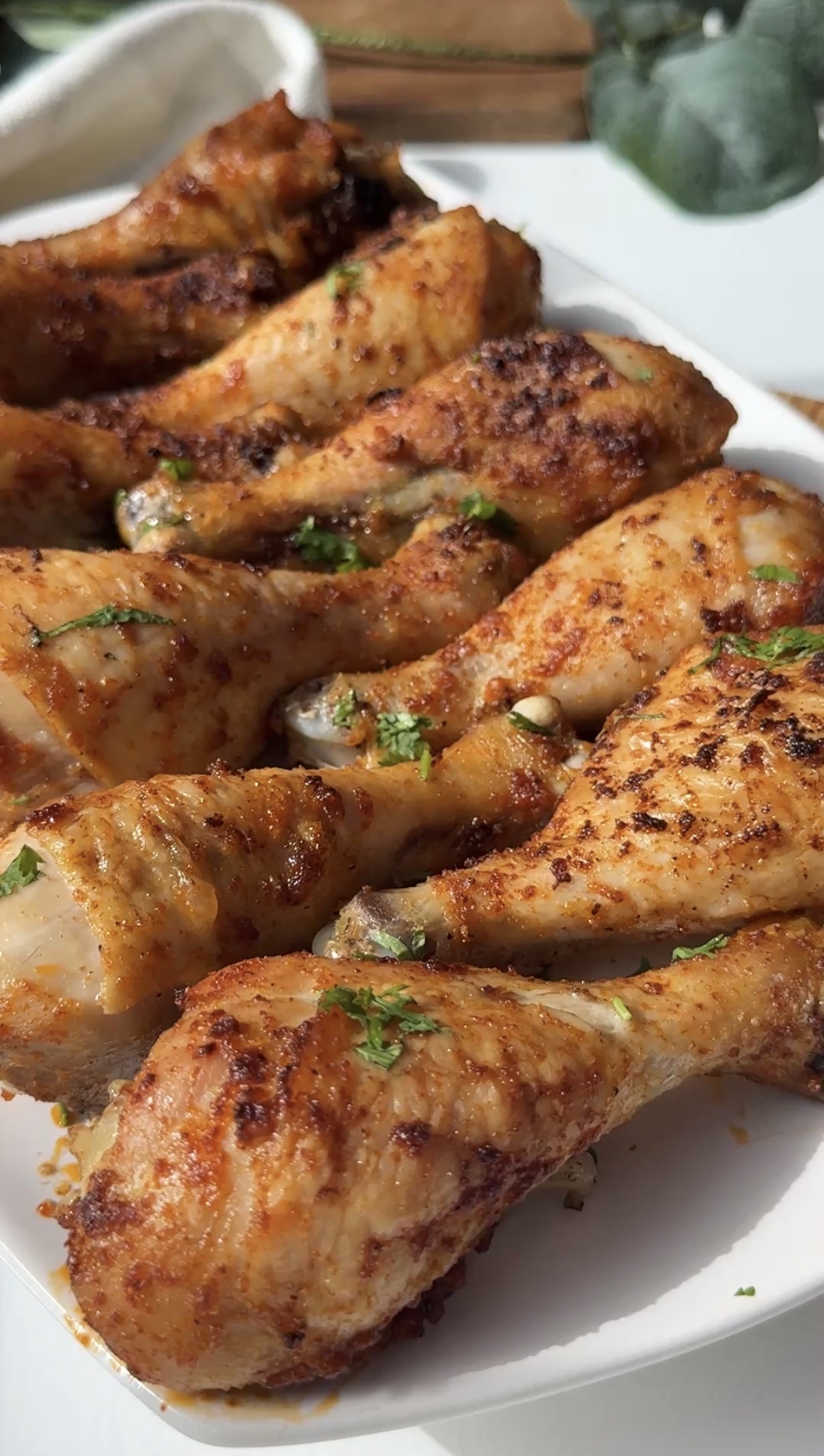 A platter of baked chicken drumsticks garnished with parsley.