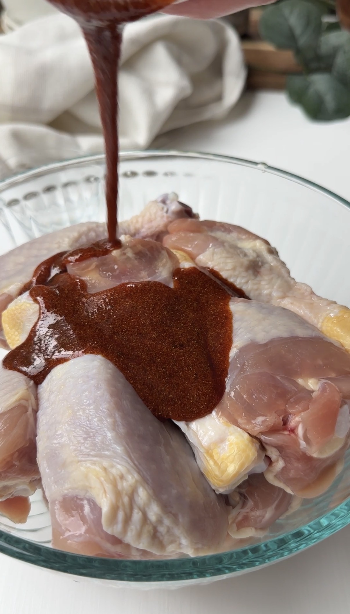 Pouring the marinade over the chicken drumsticks.