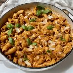 A skillet of red pesto pasta with chicken.