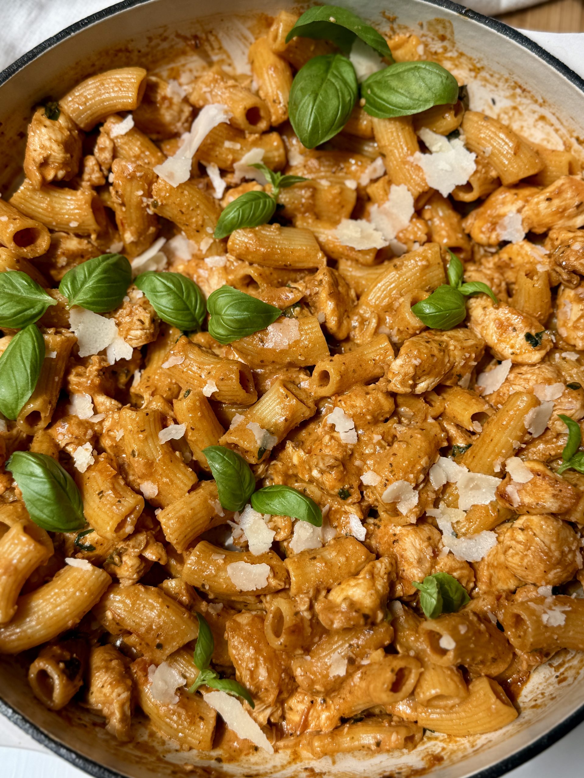 Red pesto chicken pasta in a skillet ready to serve. 