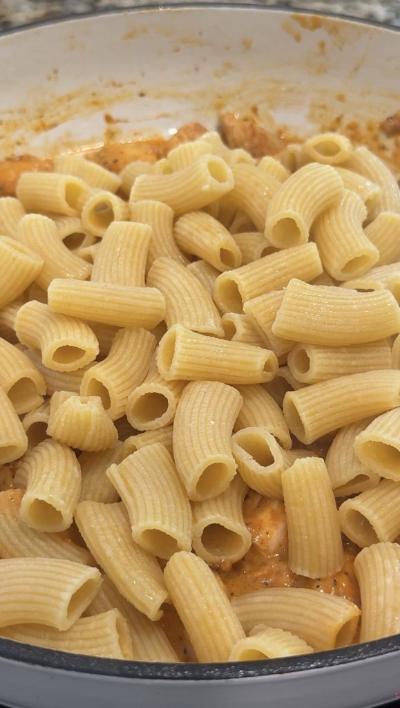 Pasta added to the skillet with the chicken and red pesto sauce. 