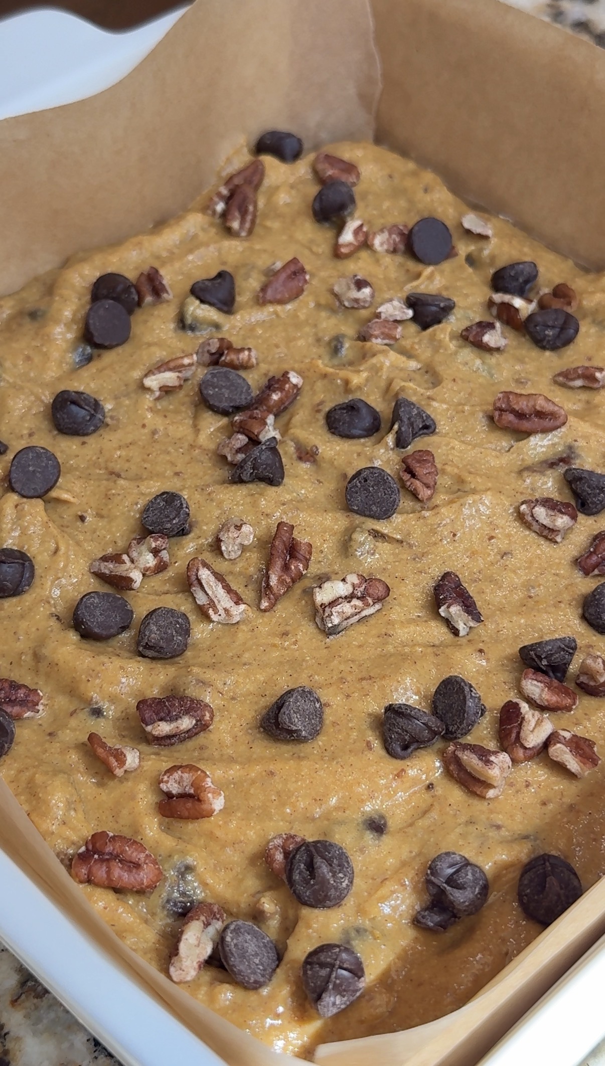 Pumpkin bar batter with chocolate chips and pecans in a 9x9 baking pan