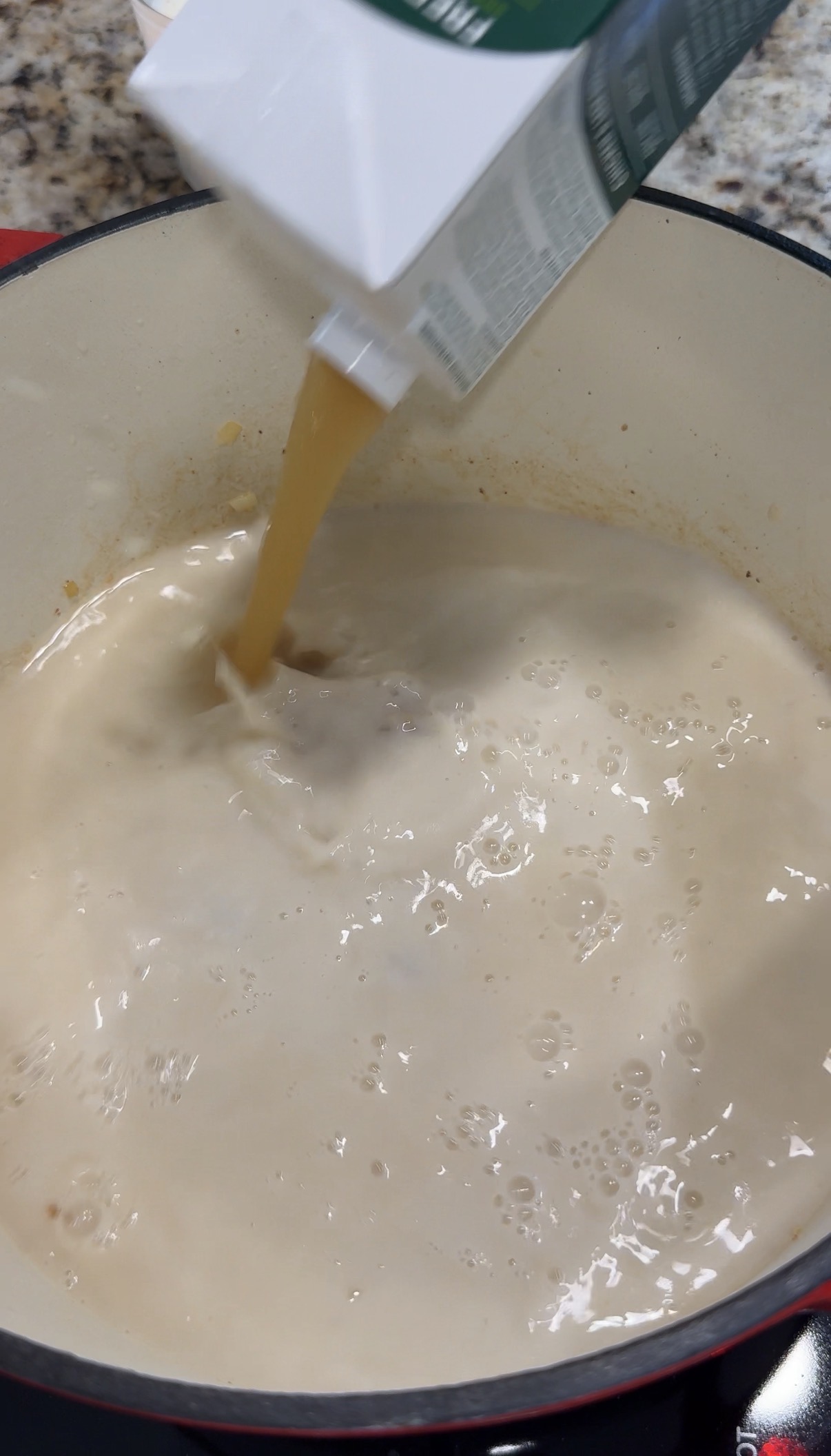 Broth being added to the onions, garlic and milk base