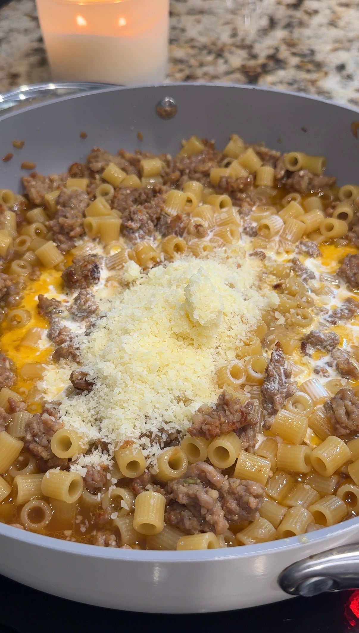 Cream and Parmesan being stirred into Italian sausage ditalini pasta