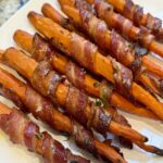 Bacon-wrapped carrots with crispy bacon and maple-thyme glaze, laid out on a white platter