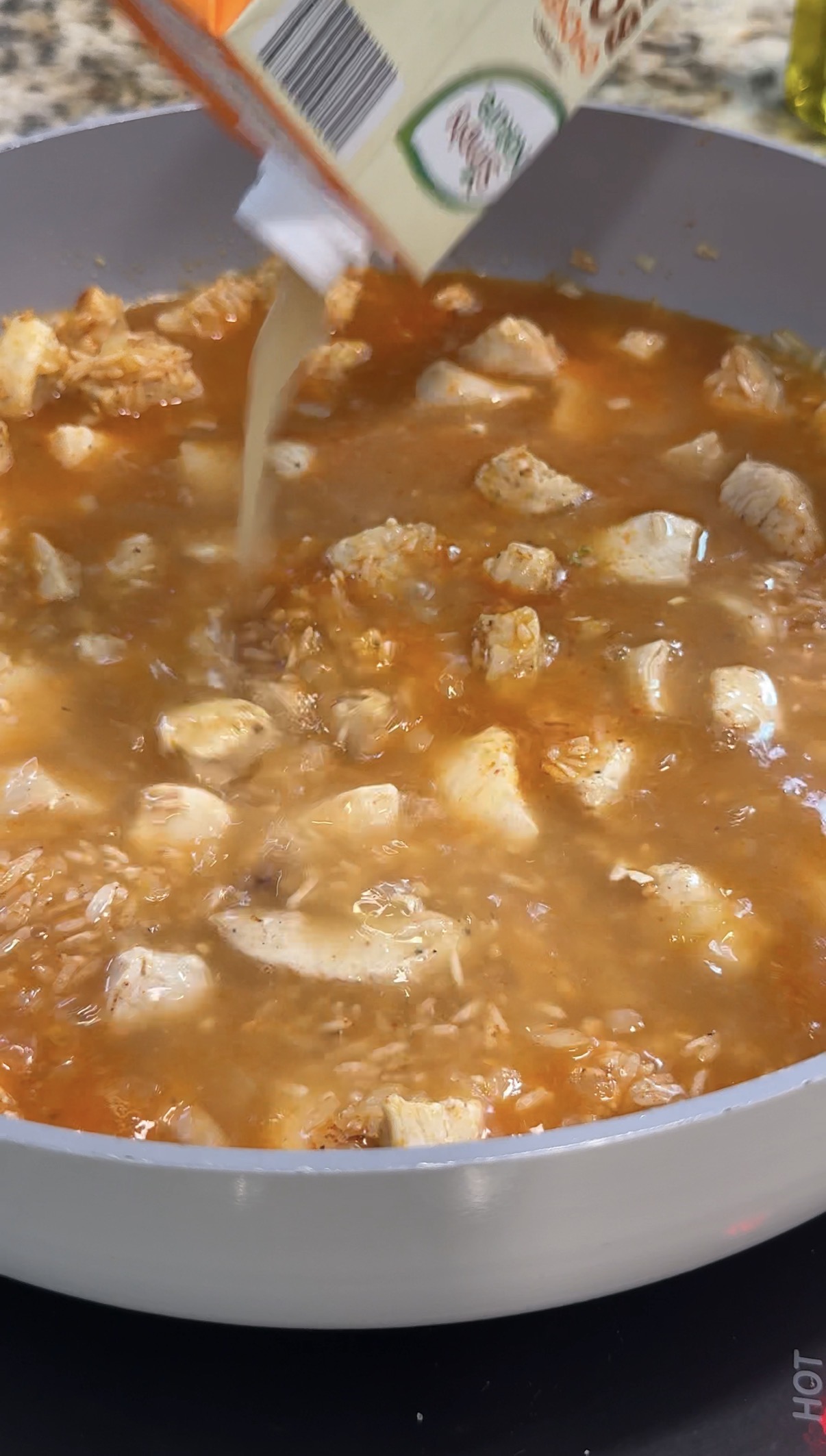 Adding the broth to the chicken and rice.