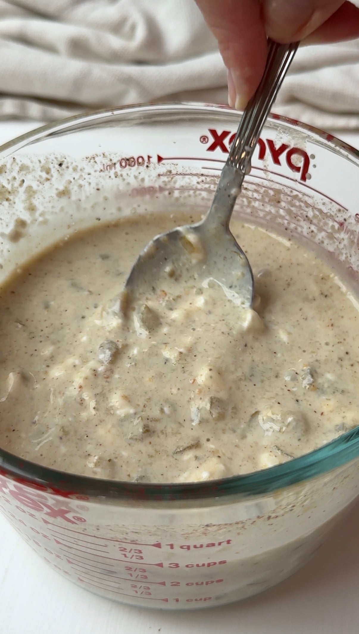 Sour cream enchilada sauce mixed together with a spoon.
