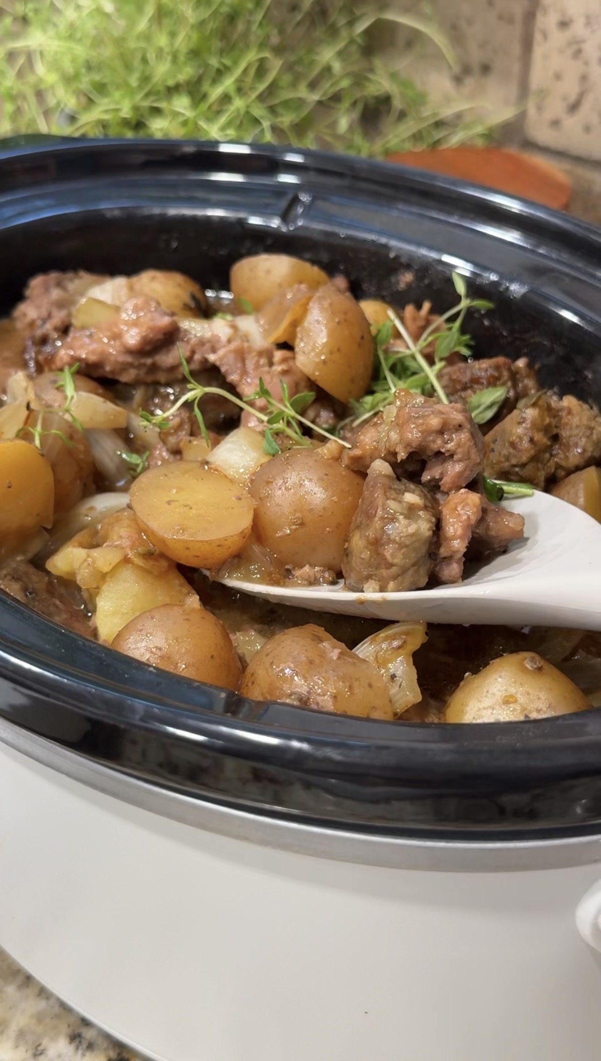 Crockpot steak bites and baby potatoes coated in savory beef gravy and garnished with fresh thyme