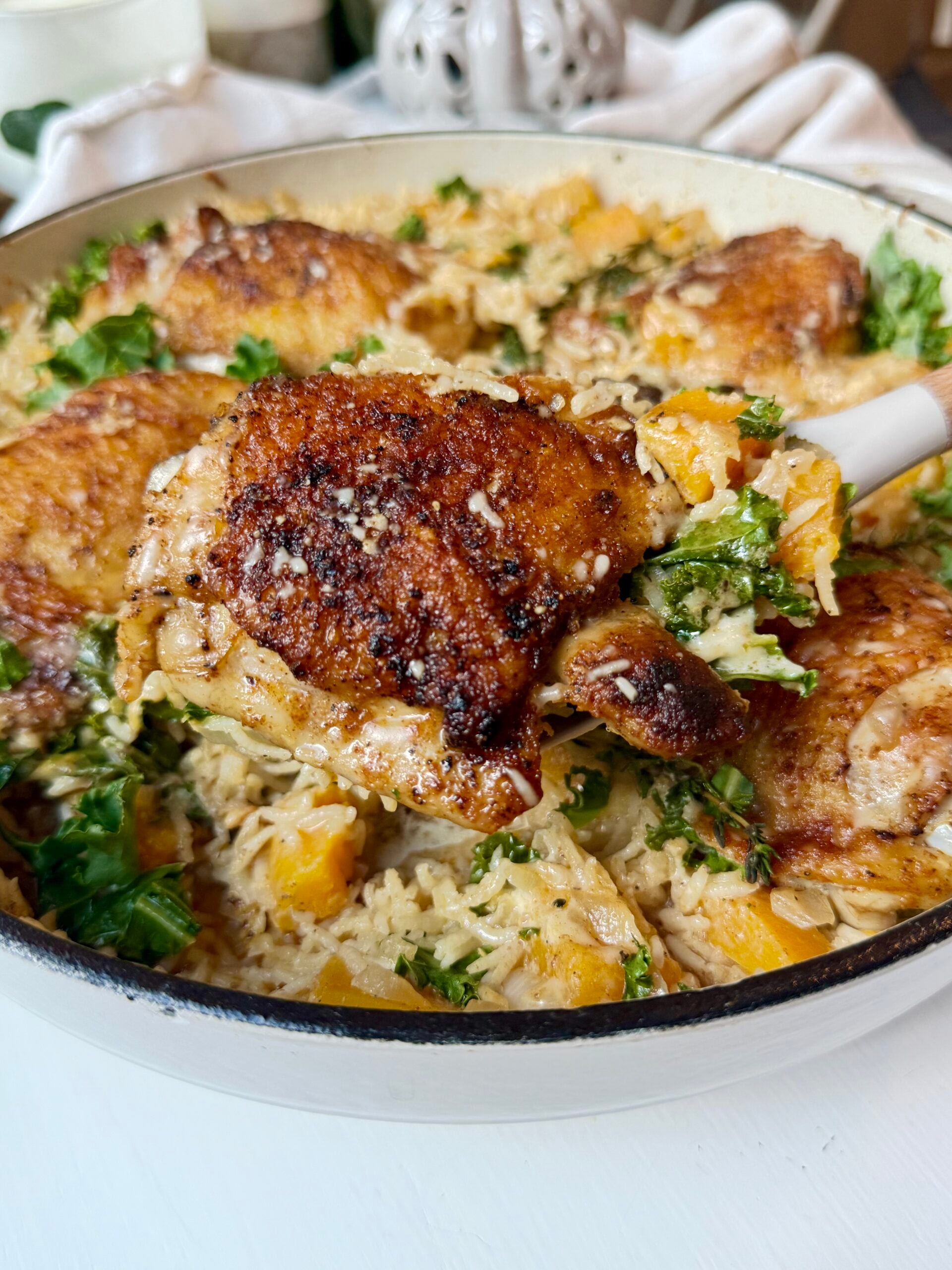 a spoon with chicken and rice with butternut squash, kale, and creamy Parmesan sauce