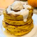 Fluffy pumpkin cinnamon roll pancakes topped with cinnamon swirl and creamy Greek yogurt glaze