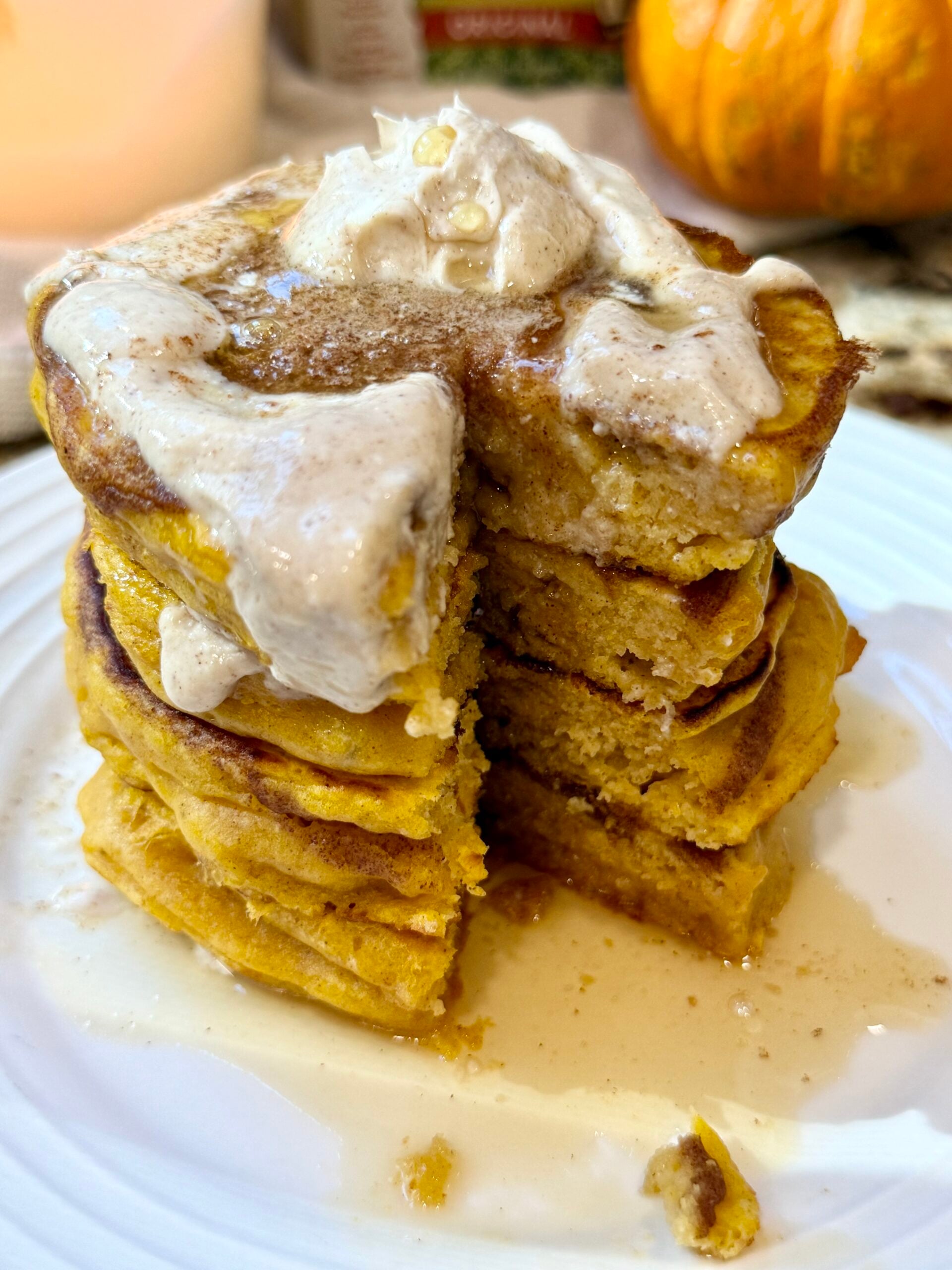 Stack of fluffy pumpkin cinnamon roll pancakes served with creamy cinnamon yogurt glaze
