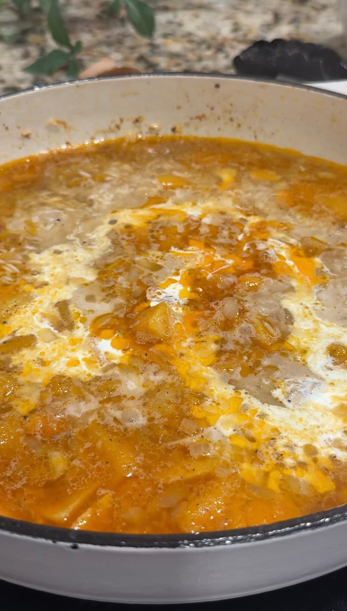Rice and diced butternut squash simmering in broth with browned chicken thighs