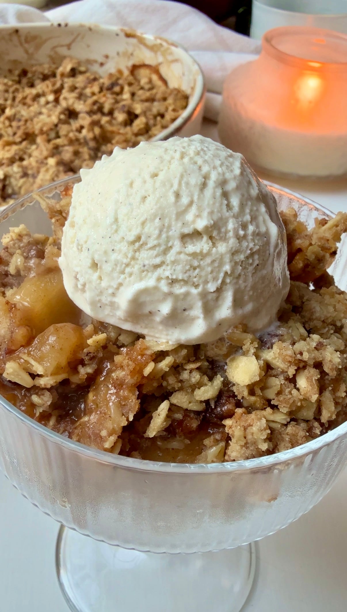 Warm apple crisp with a buttery pecan oat topping served with a scoop of vanilla ice cream
