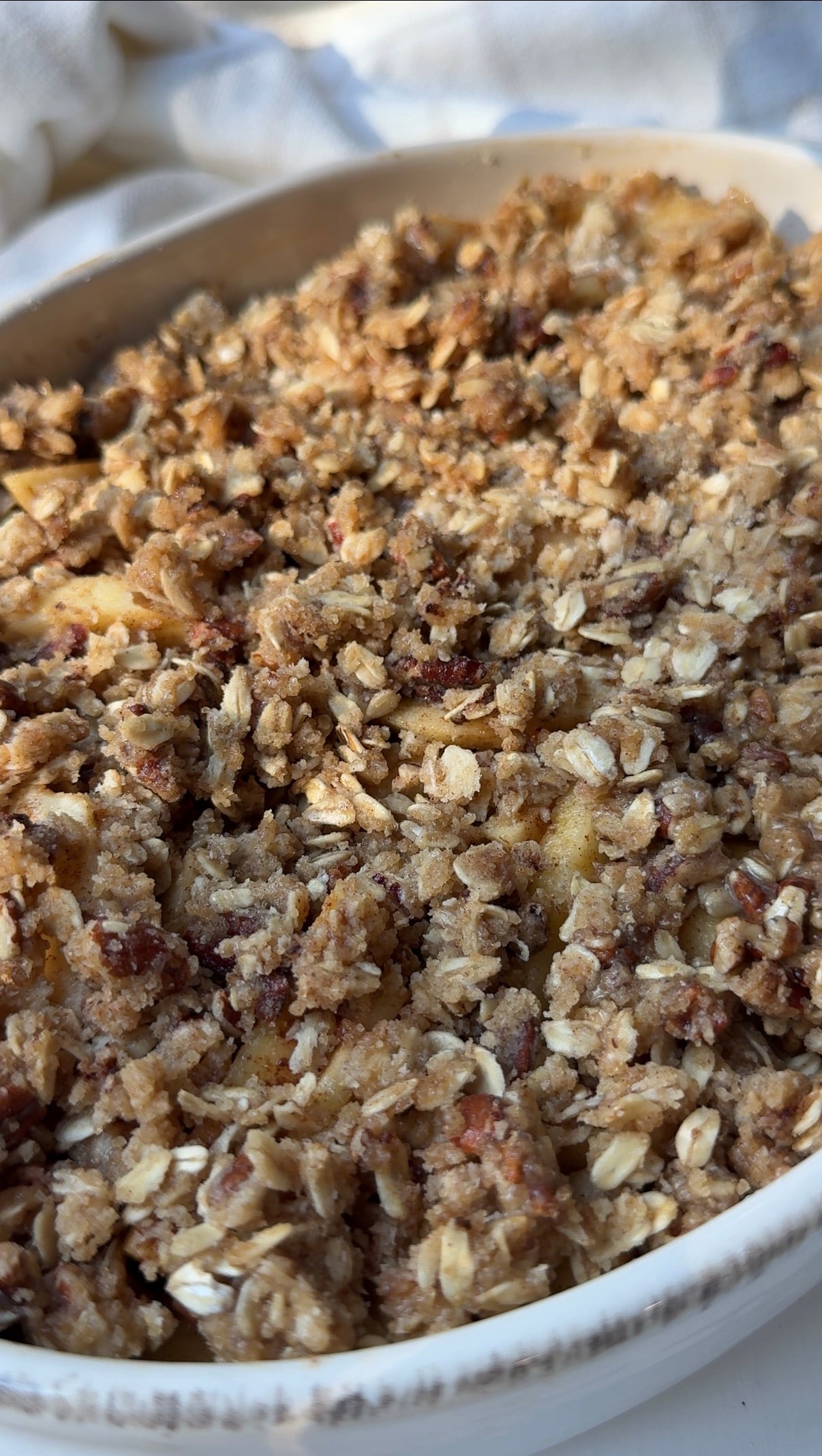 Sliced cinnamon apples covered with an oat and pecan crumble in a baking dish