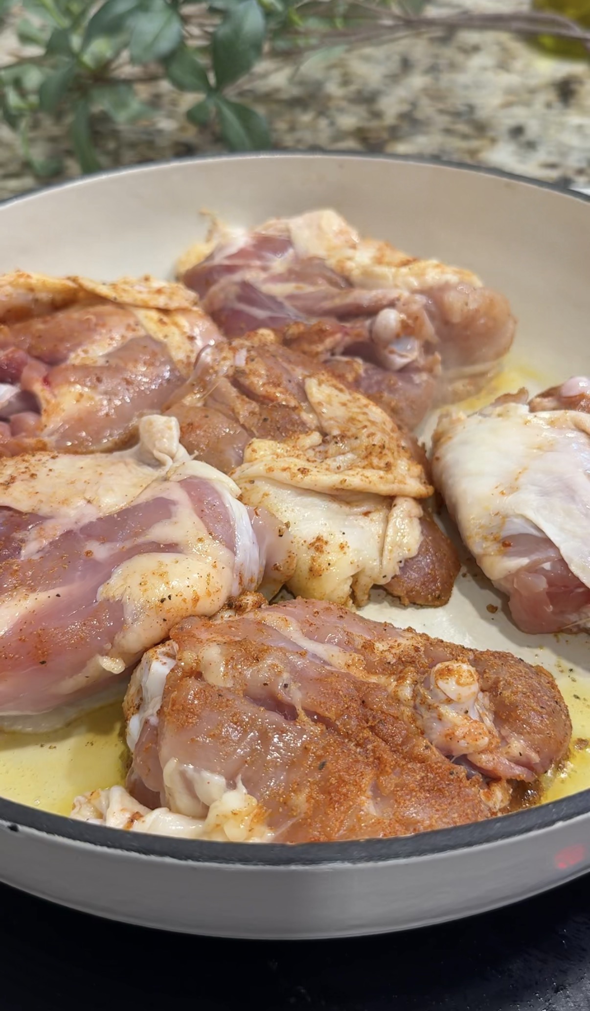Chicken thighs browning in a skillet before cooking with rice and butternut squash